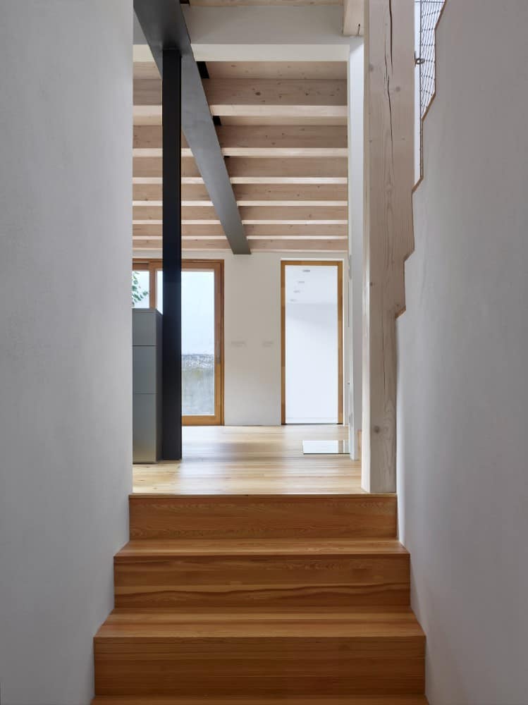 Interior shot of wooden staircase facing on a huge frosted window with wooden frame accent.