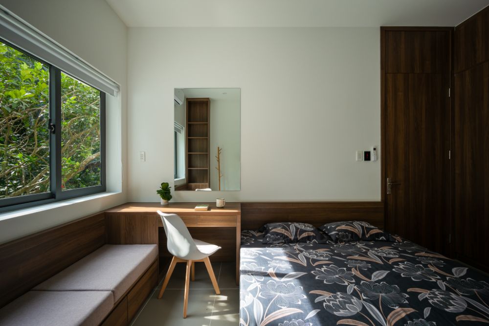 Bedroom with walnut wood bed, cabinet, table and sofa in an open window leading to view the outside.