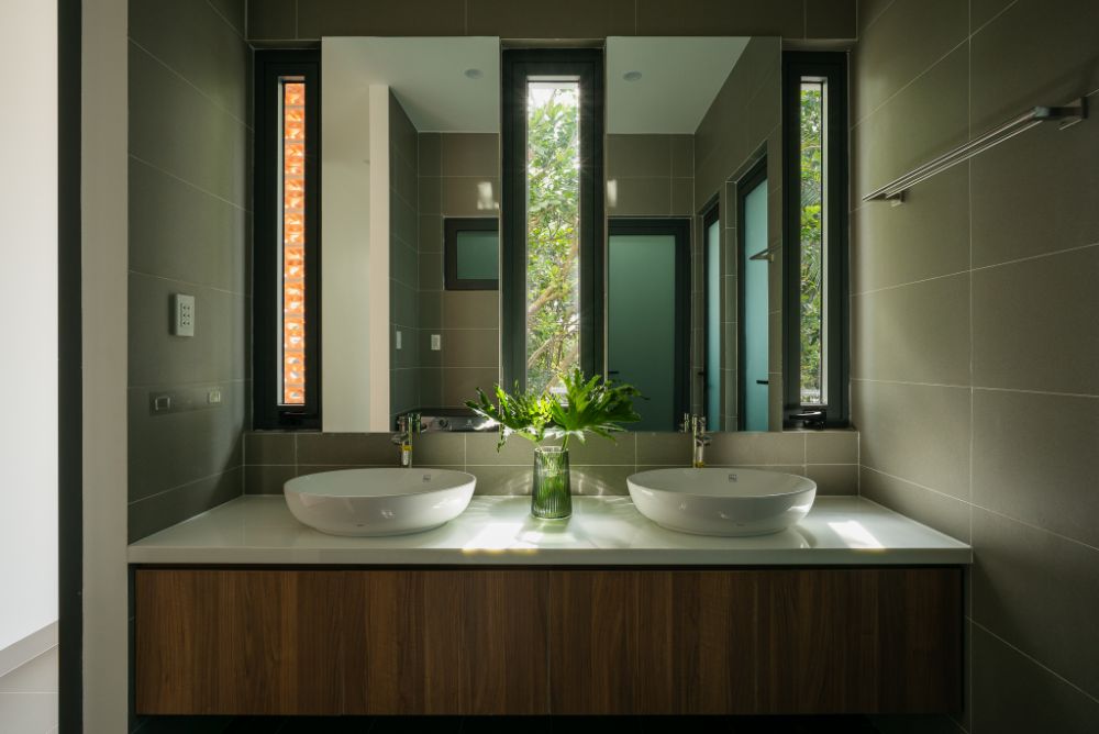 Bathroom sink with full length mirror and two table-top white oval sinks.