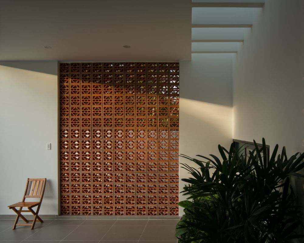 Ventilation brick wall with wooden chair and plant.