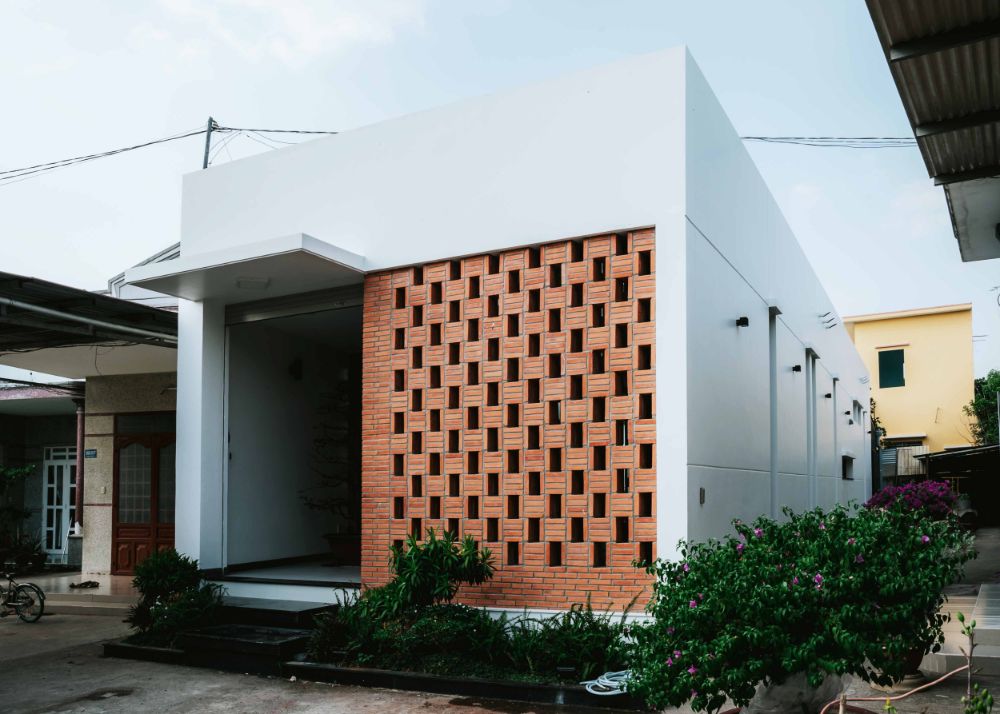 White rectangular small house with roofless design and decorative bricks front wall.