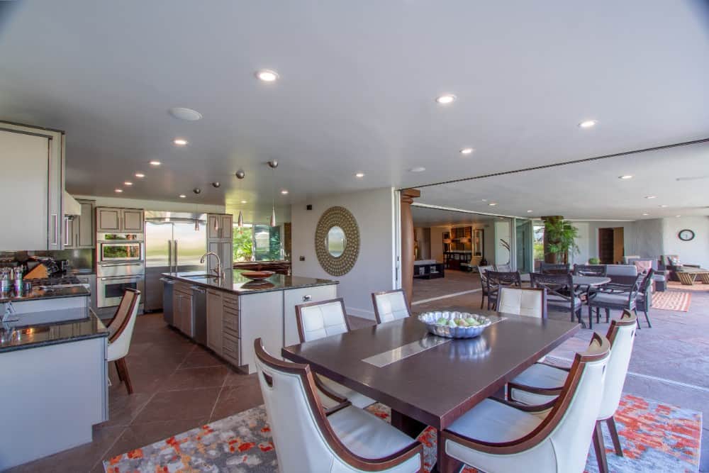 Eat-in kitchen with gray cabinets, a prep island, and a 6-seater dining set. Image courtesy of Toptenrealestatedeals.com