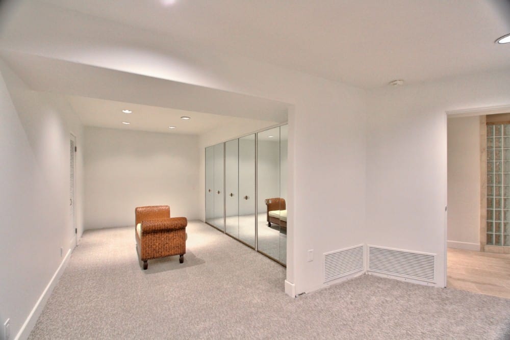 A spacious walk-in closet with a Cleopatra bench and mirrored cabinets. Image courtesy of Toptenrealestatedeals.com