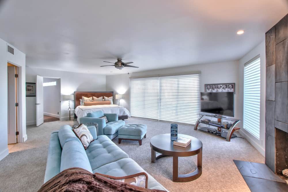 JFK primary bedroom with massive windows, a fireplace, and a spacious sitting area. Image courtesy of Toptenrealestatedeals.com