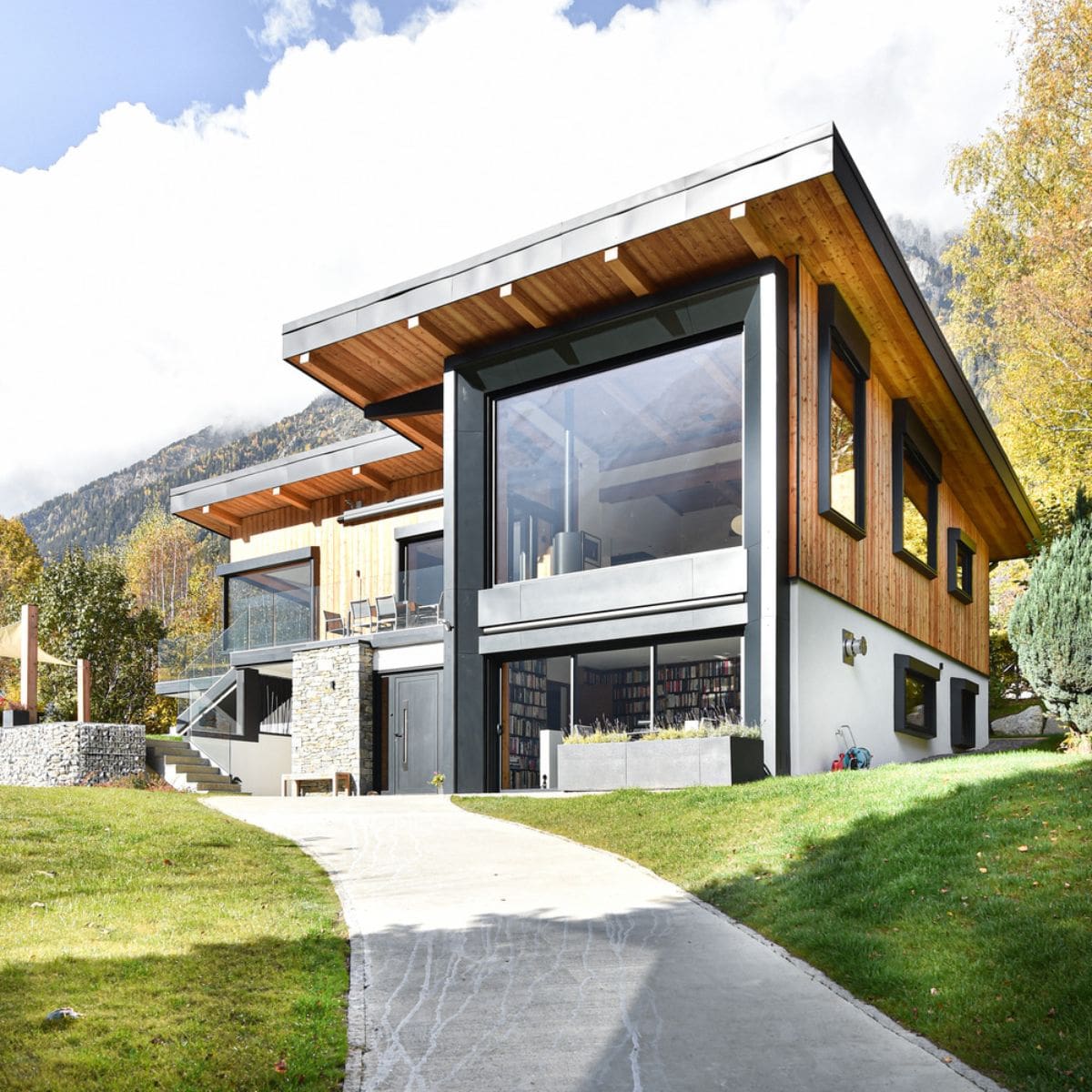 A view of the two story house surrounded with lush greenery and grass.