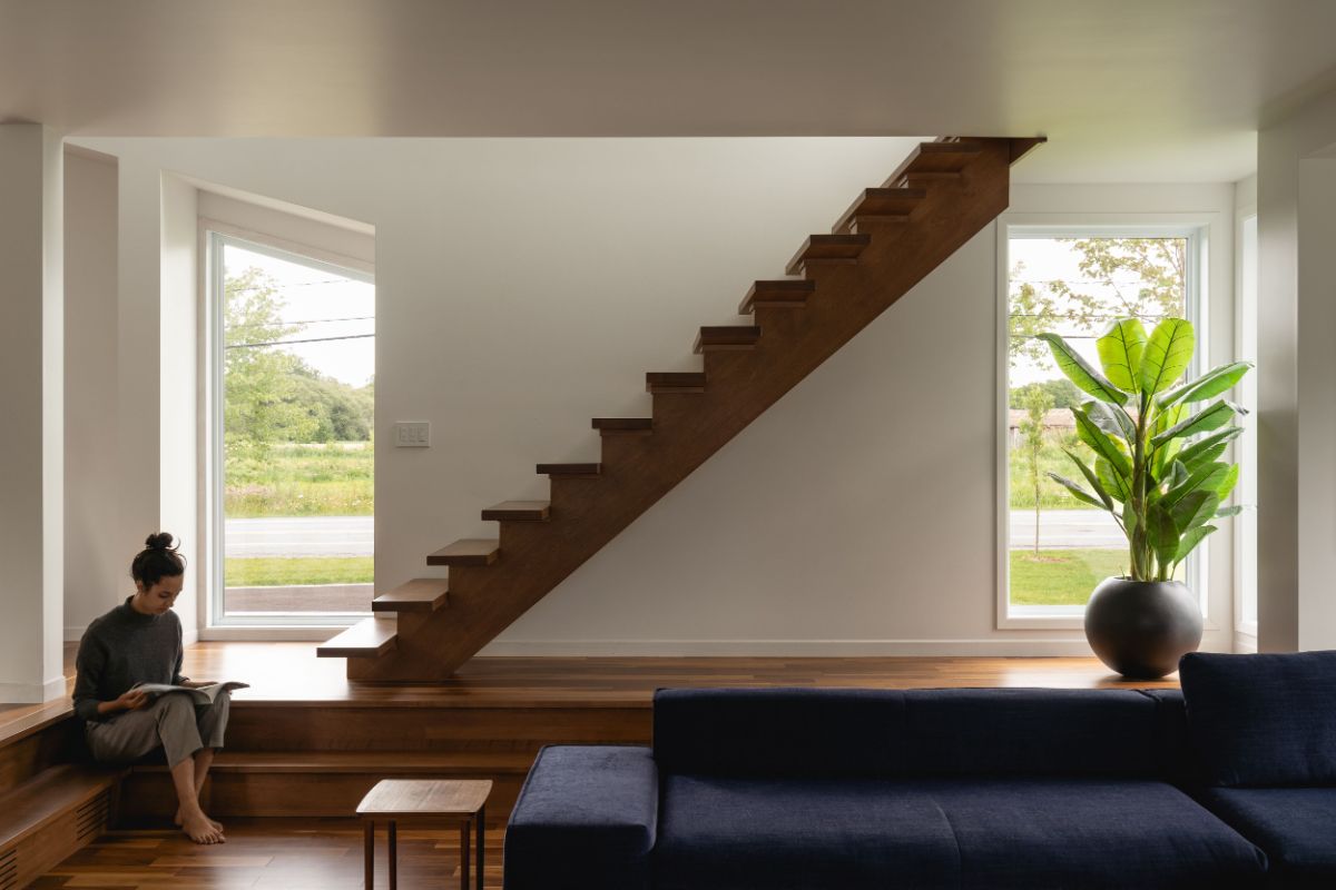 The main entrance with white wood wall and wooden floor and stairs flooded with sunlight.