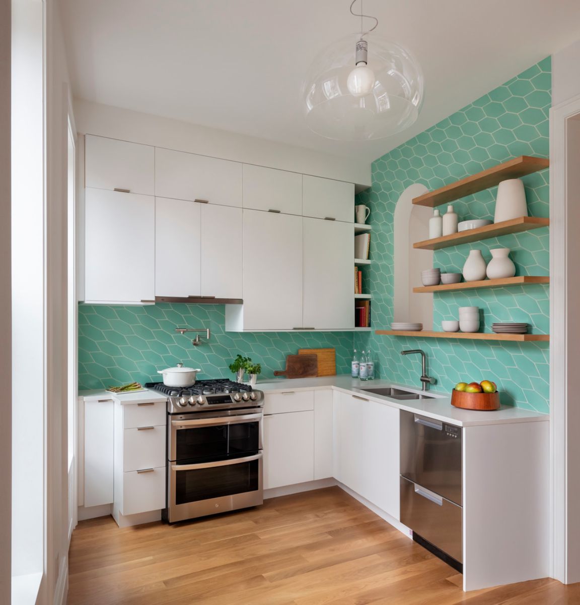 The L-shaped kitchen features a picket-style bright green Fireclay tile with open white oak shelving.