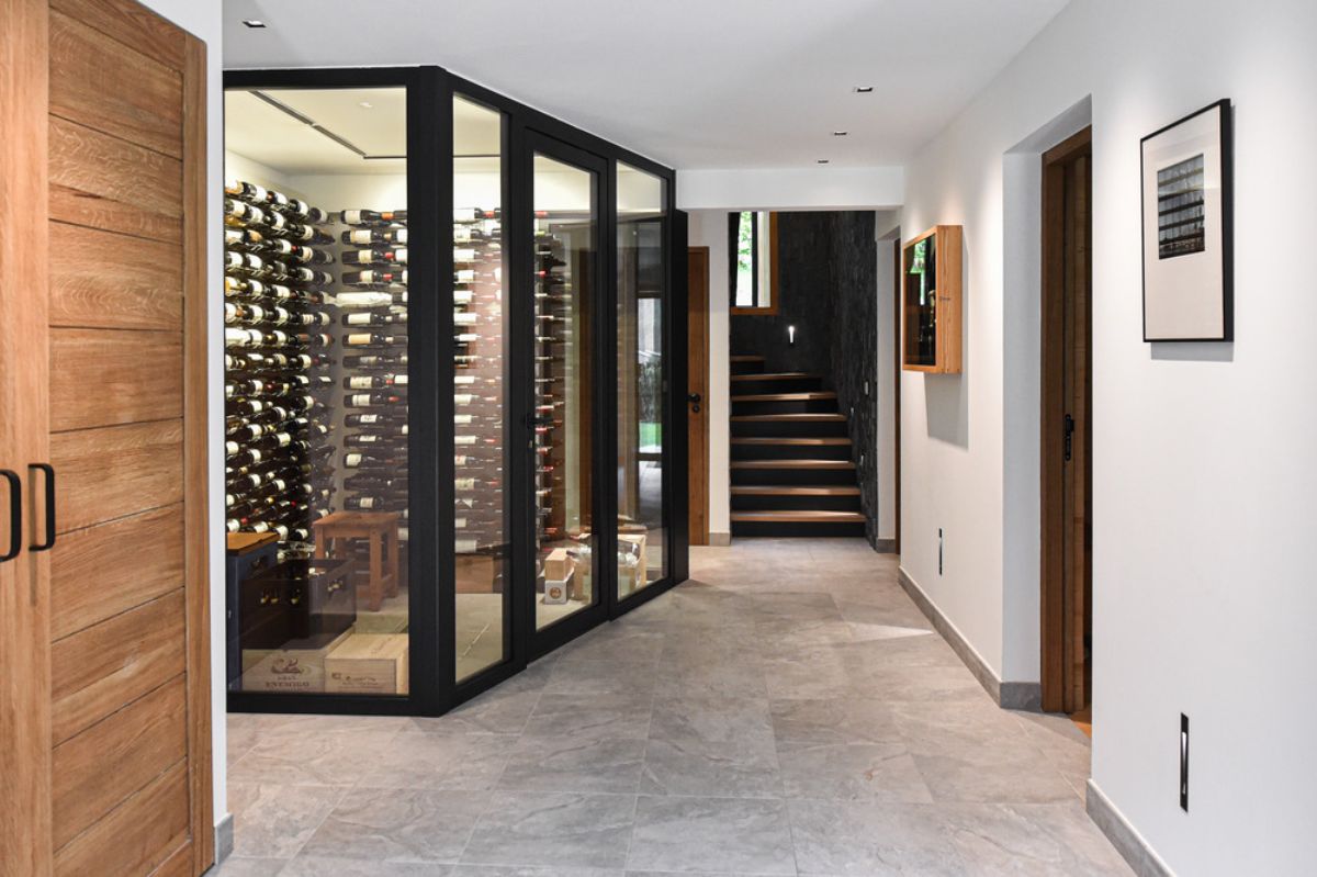 The glass-enclosed wine cellar contains different types of wine.