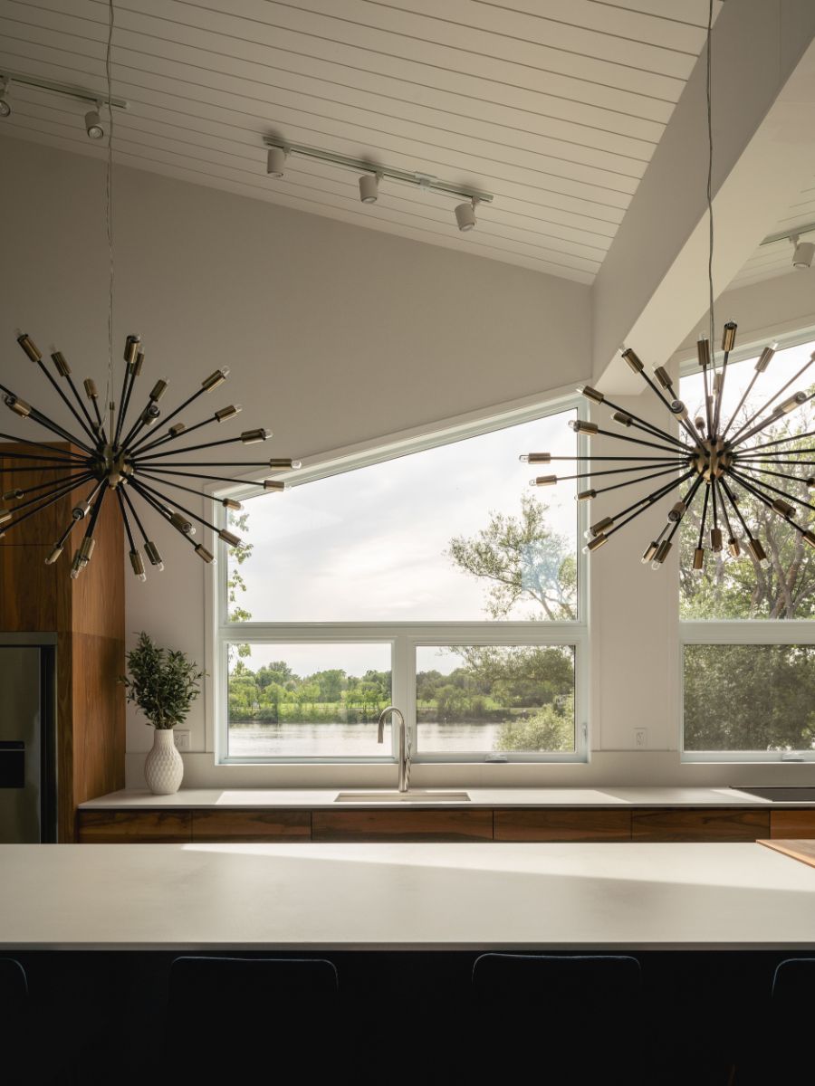 The kitchen with an imposing central island, customized lighting and large windows allowing to gaze out the flowing river.