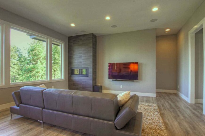 The great room includes a leather sofa, a modern fireplace, and a wall-mounted TV.