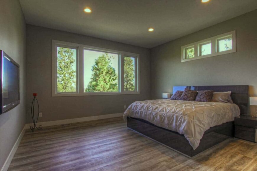 Primary bedroom with hardwood flooring, a custom bed, and clerestory windows that invite natural light in.