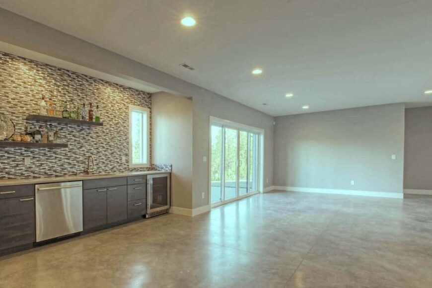 Spacious family room with direct patio access and a wet bar highlighted with linear mosaic tiles.