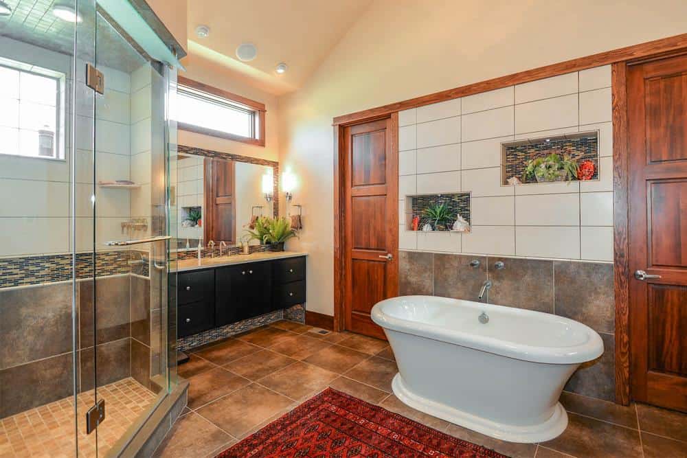 Primary bathroom with dark wood vanity, a walk-in shower, and a freestanding tub complemented with a red rug.