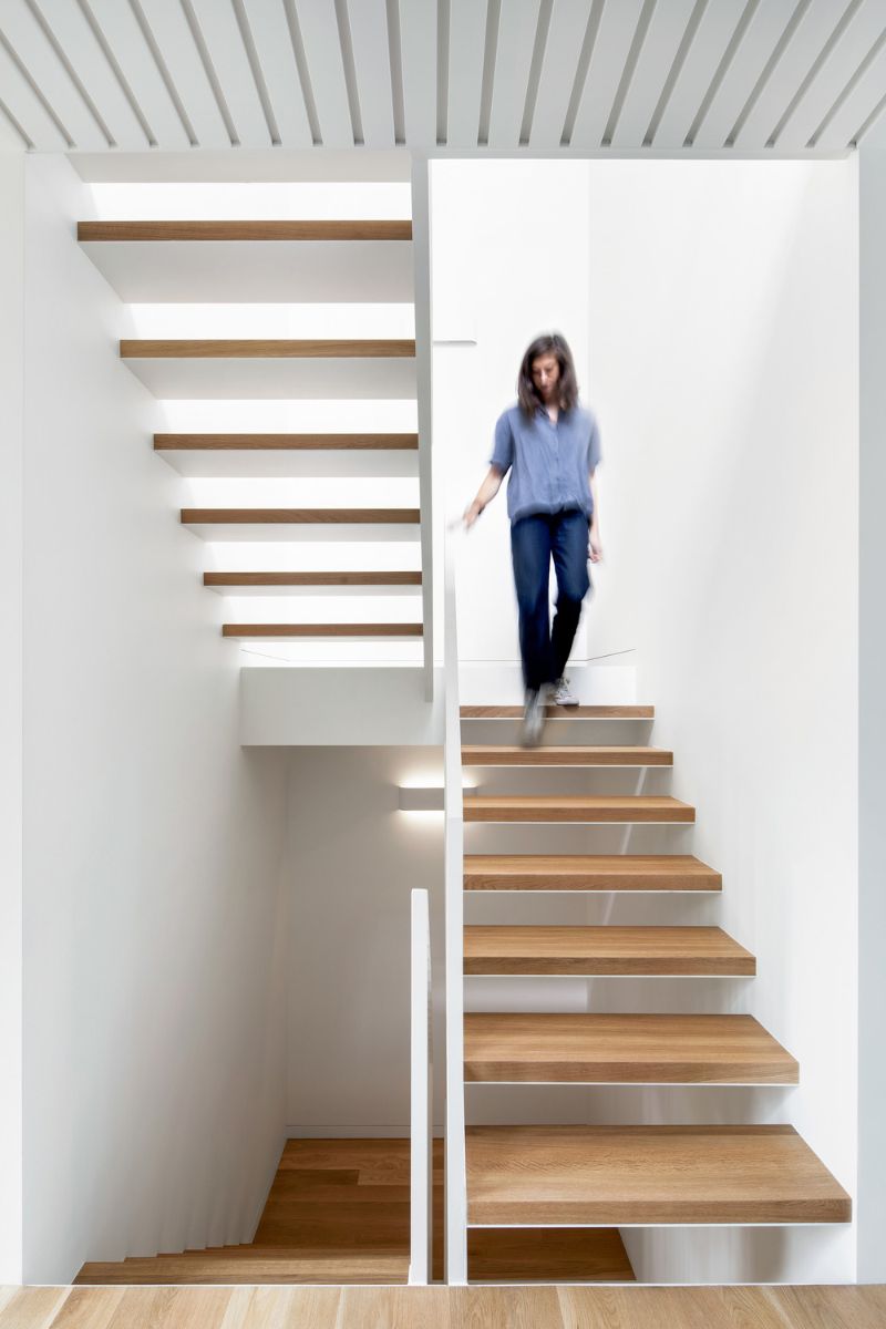 A woman stepping down the stairs from the upper level.