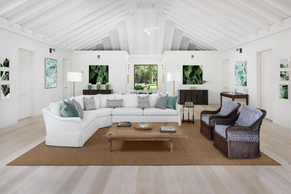 Main residence living room with an L-shaped sectional and wicker armchairs sitting on a jute area rug. Image courtesy of Toptenrealestatedeals.com.