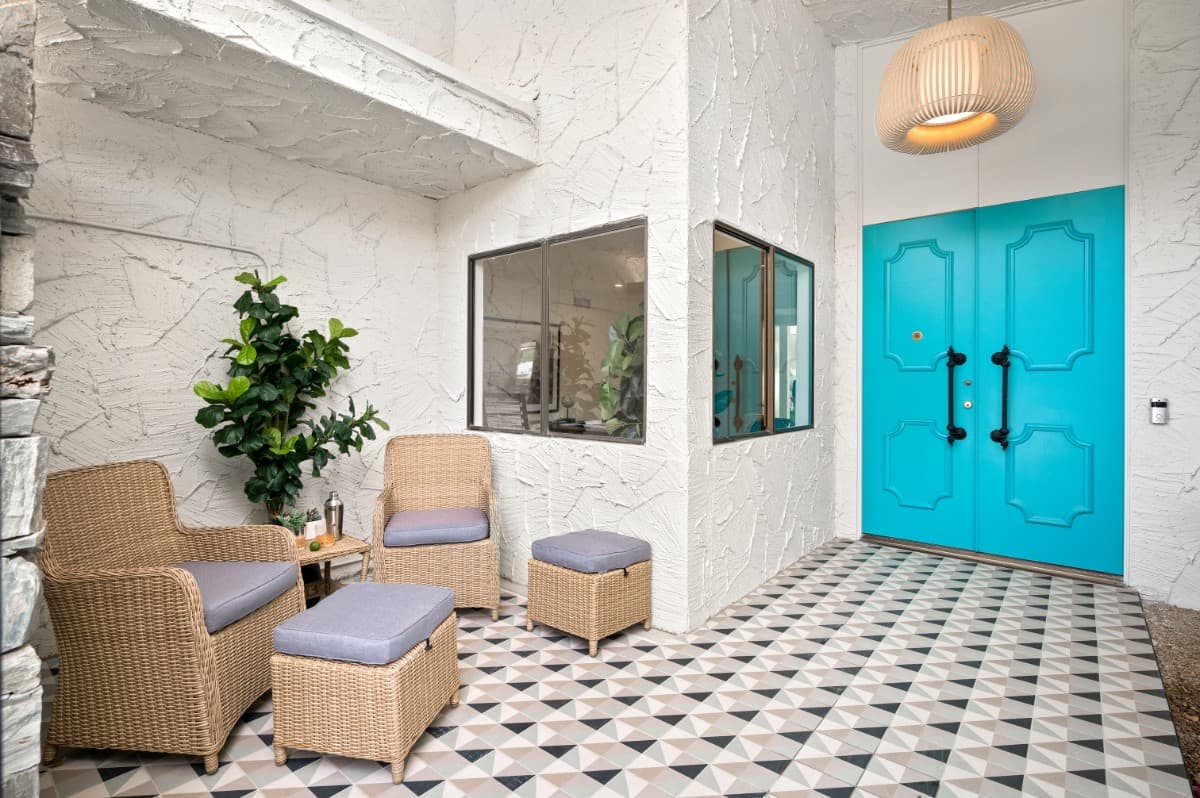 The foyer features a blue double front door that stands out against the white textured walls and geometric floor. Image courtesy of Toptenrealestatedeals.com.