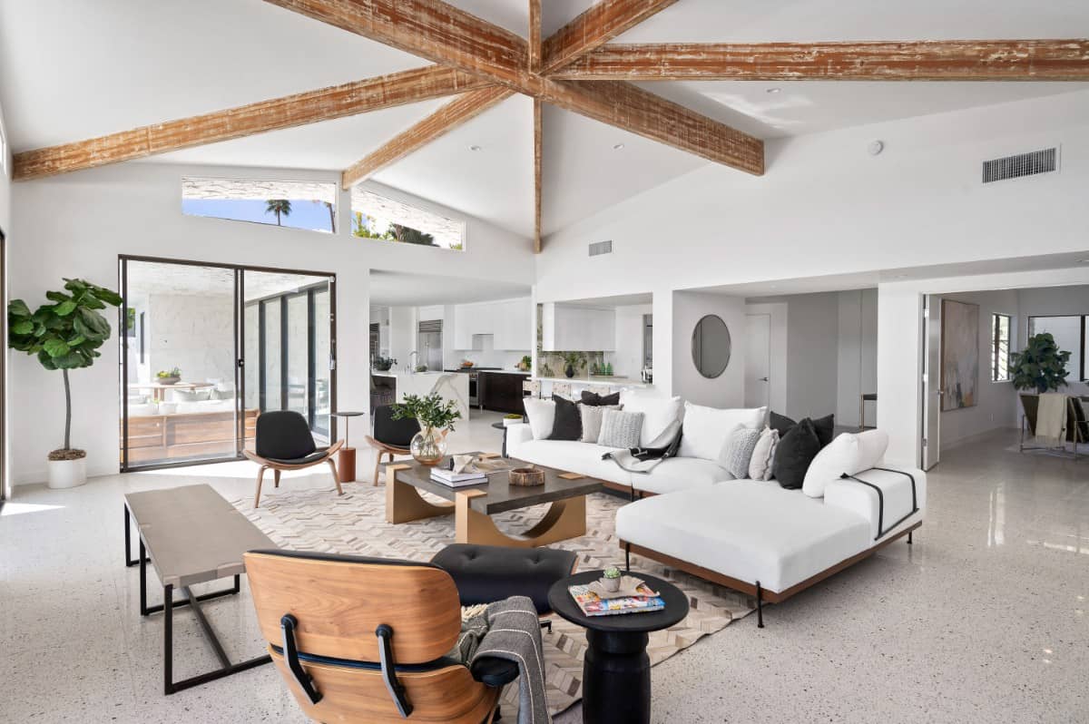 Living room with contemporary furnishings and a hand-scraped douglas fir and wood-beamed umbrella roofline that contrasts the pristine white walls. Image courtesy of Toptenrealestatedeals.com.