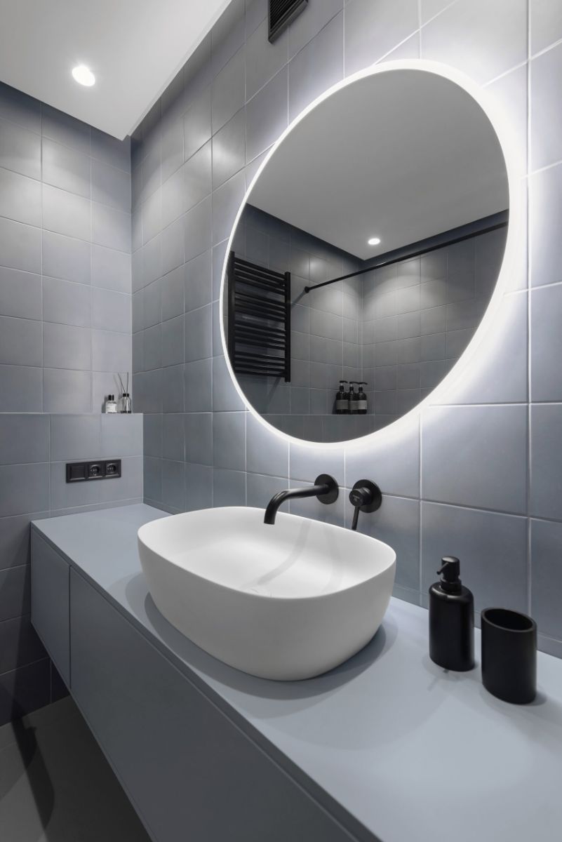 The bathroom sink with a round vanity and lighting behind it.