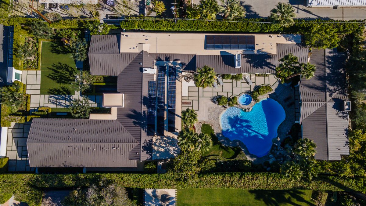 An aerial view of the house, emphasizing the turquoise swimming pool and surrounding nature. Image courtesy of Toptenrealestatedeals.com