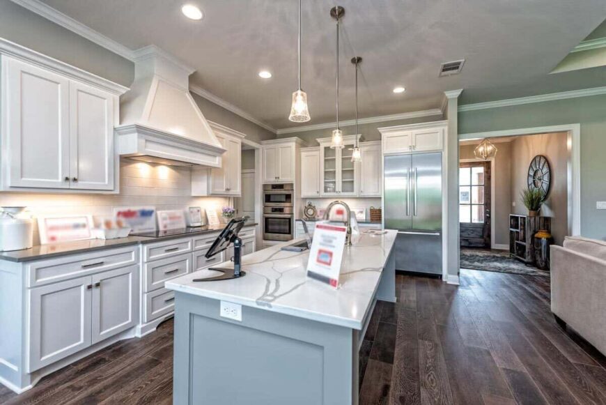 The kitchen is equipped with stainless steel appliances, white cabinetry, marble countertops, and a breakfast island.