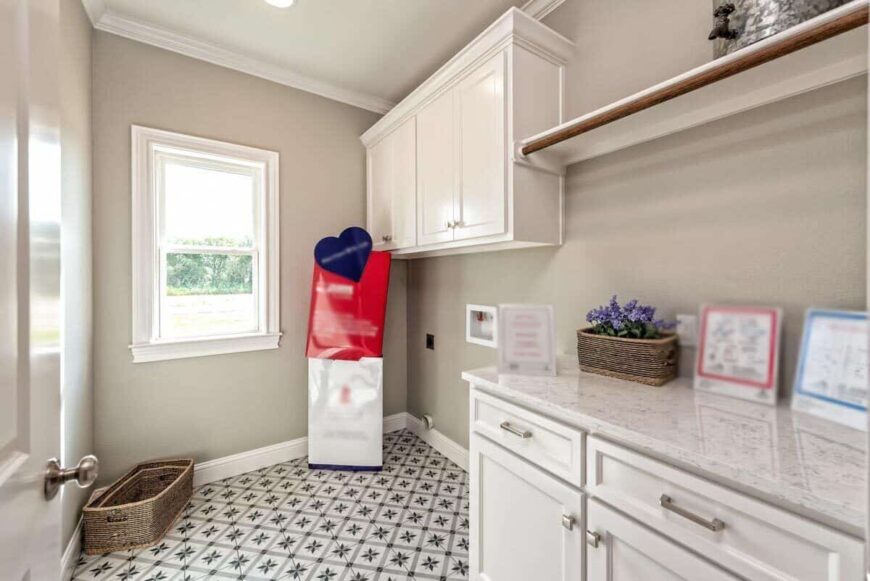 Laundry room with white cabinets, a quartz countertop, and decorative tile flooring.