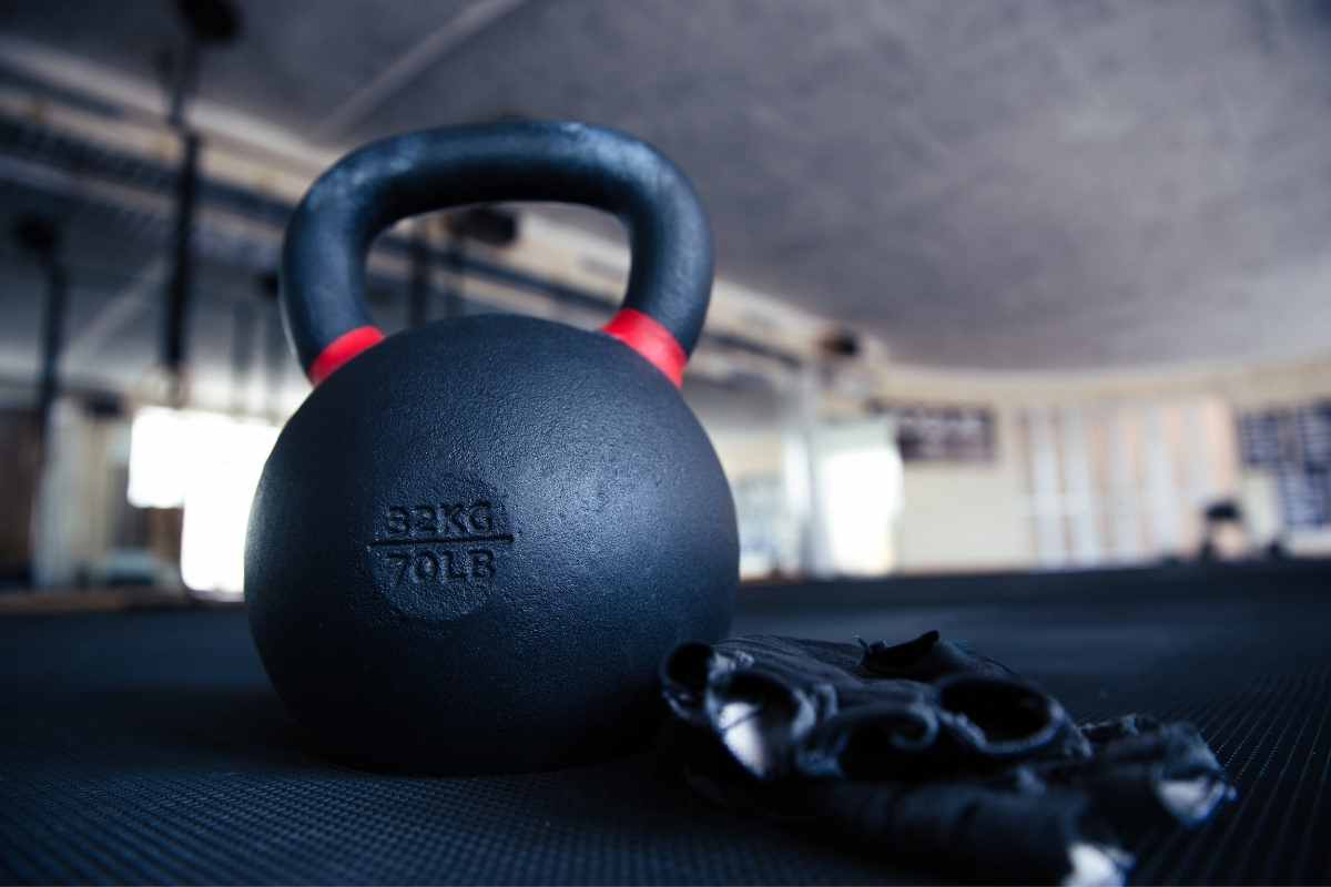 Closeup image of a kettle ball and sports gloves in gym.