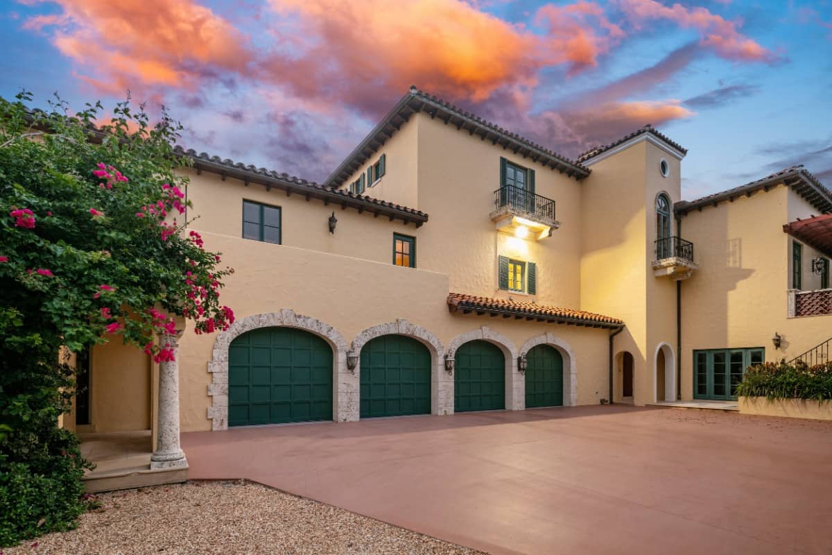 A six-car garage enclosed in large, green-paneled doors adds to the home's curb appeal. Image courtesy of Toptenrealestatedeals.com.