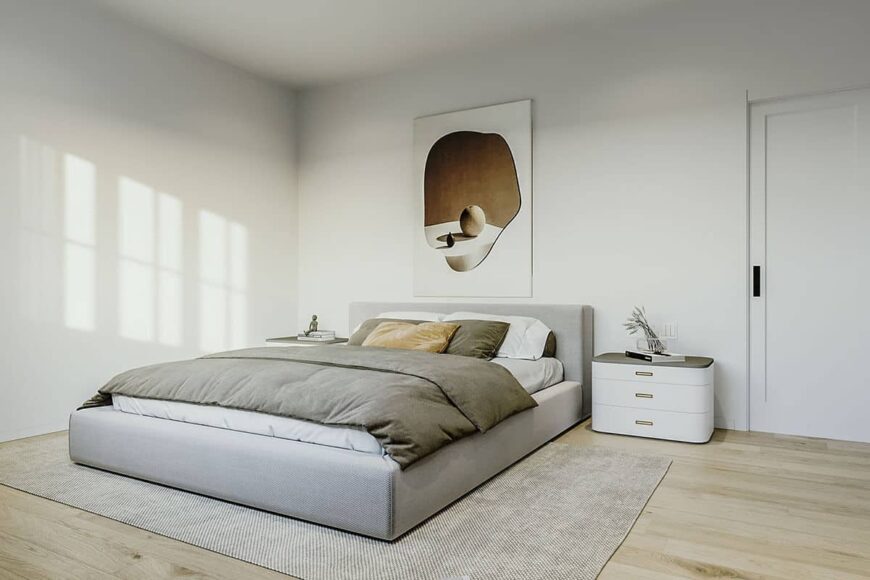 Primary bedroom with a gray platform bed, modern nightstands, and lovely artwork adorning the stark white walls.