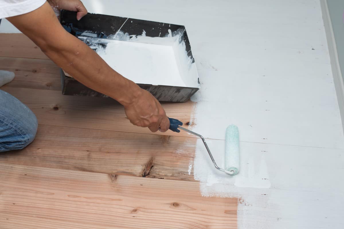 Painting vinyl floor with roller brush.