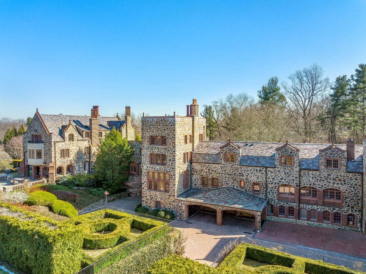 The castle's front, which has a beautiful view of the formal garden, a gabled roof, and stone exterior walls. Image courtesy of Toptenrealestatedeals.com