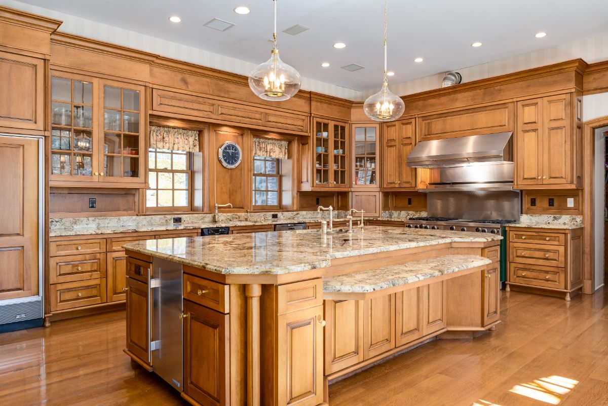 The chef's kitchen is outfitted with granite countertops, a large central island, and a professional-grade gas range. Image courtesy of Toptenrealestatedeals.com