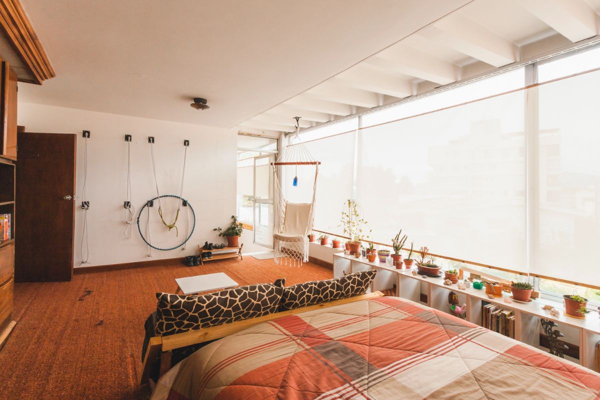 The bedroom with large glass window and lined of plants in the windowsill.