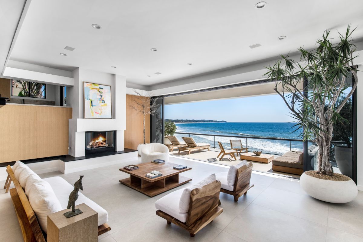 A large living room with a large sliding door leading to the deck overlooking the ocean. Image courtesy of Toptenrealestatedeals.com