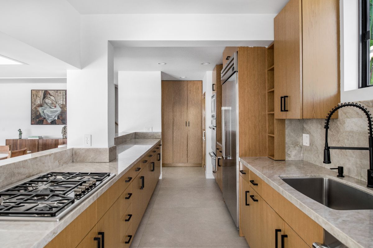 A chef's kitchen with marble countertops, wooden shelves, and high-end appliances. Image courtesy of Toptenrealestatedeals.com