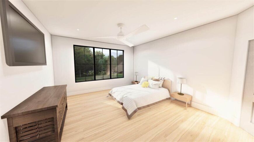 The primary bedroom has a hardwood floor, a TV, and a trio of windows overlooking the backyard.