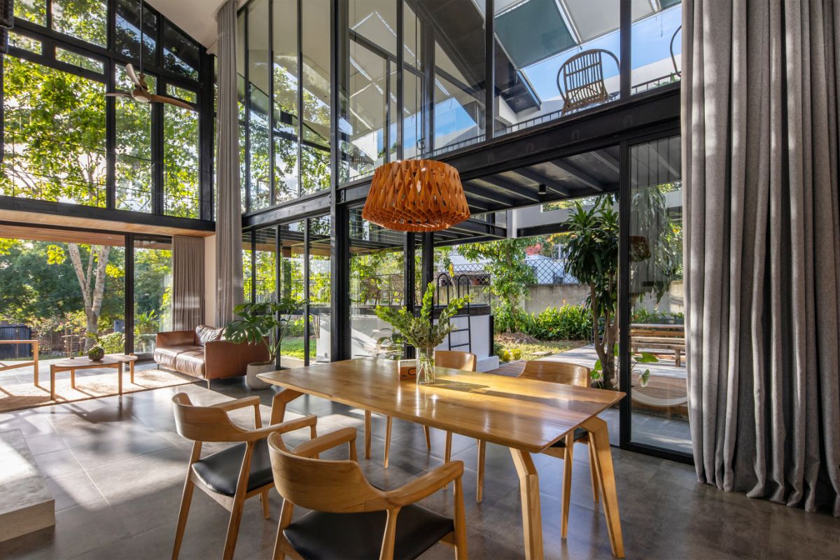 The double height dining area that features the glass wall and doors leading to the landscaped backyard.