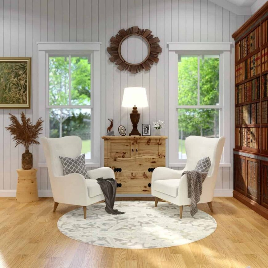 Sitting room with white wingback chairs, a built-in bookcase, and a wooden table topped with a table lamp and various decors.