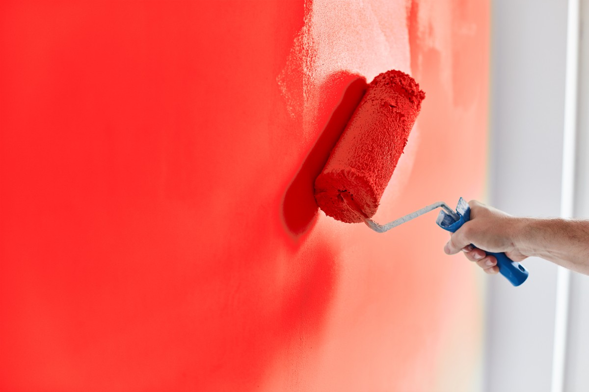 Man hand painting the wall using roller brush.