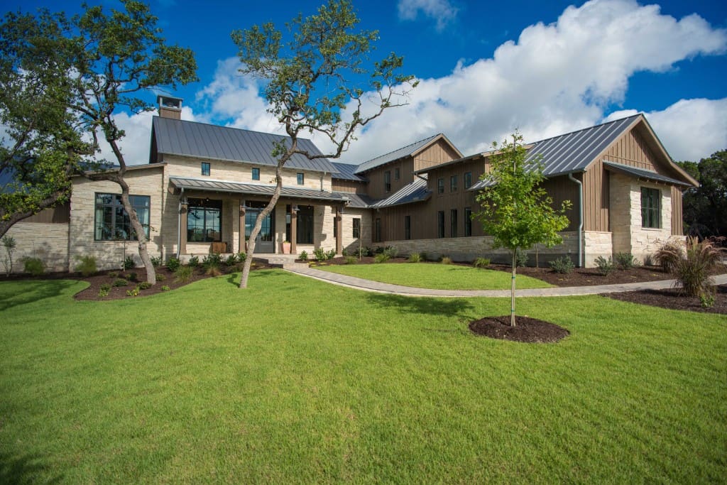 The home's facade is embellished with wood and brick siding, metal roofs, and timber posts framing the covered entry porch.