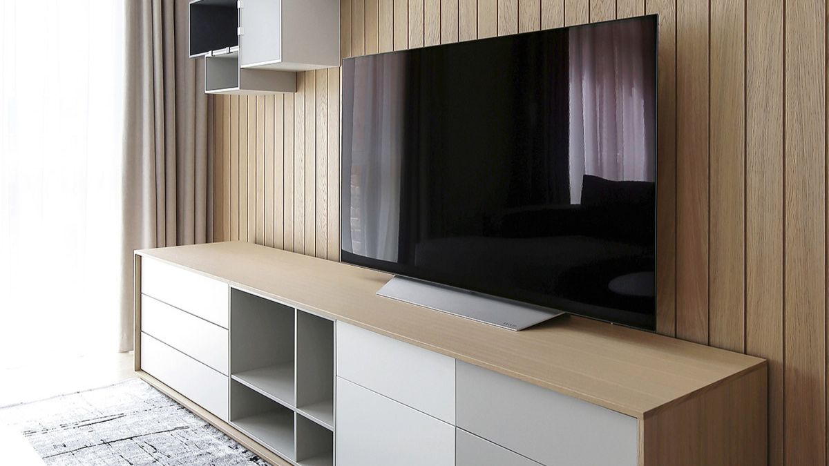 Another clear angle of the living room with a wide flat screen TV on wooden furniture.