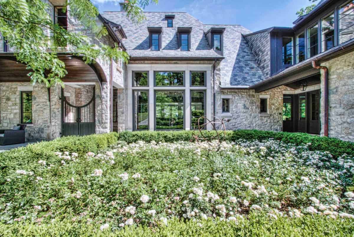 The home includes huge windows and a wrought iron gate complemented with an arched awning.