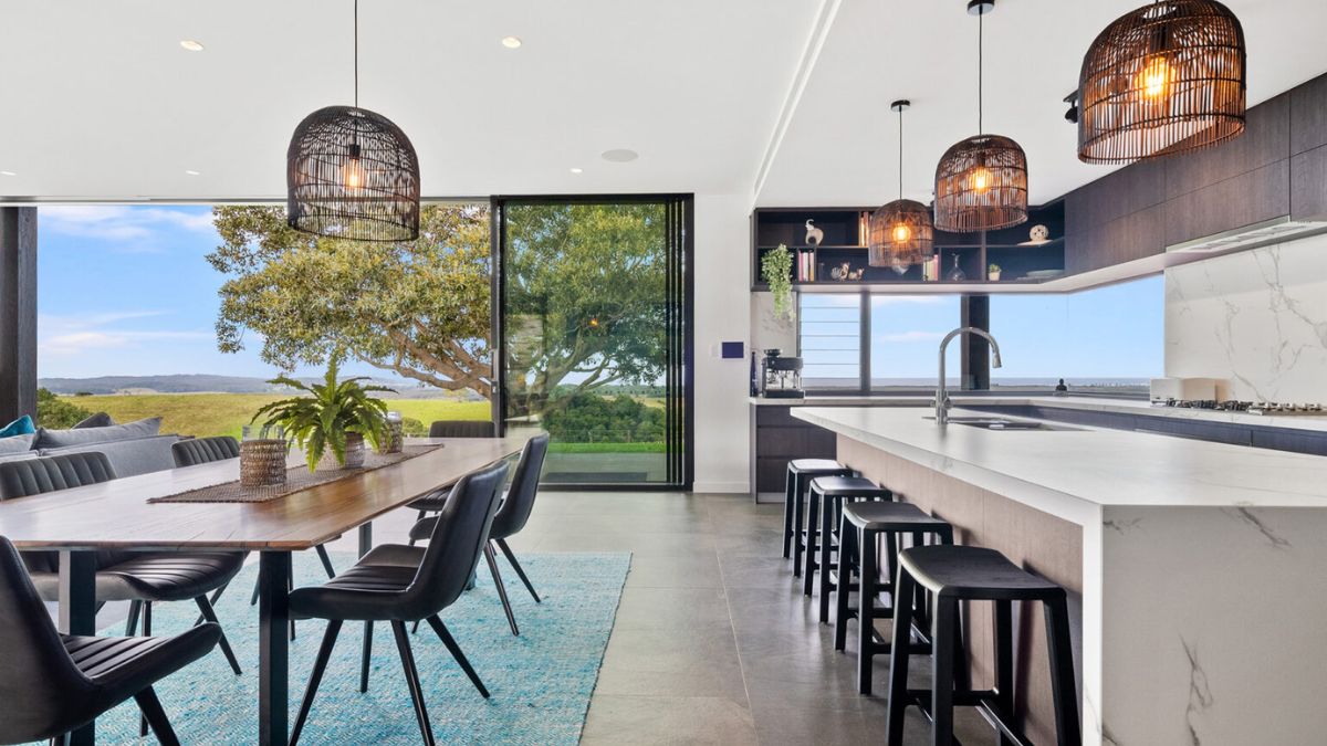 The interior of the kitchen and dining room boasts a sleek center island with a sink, providing ample counter space and functionality. 