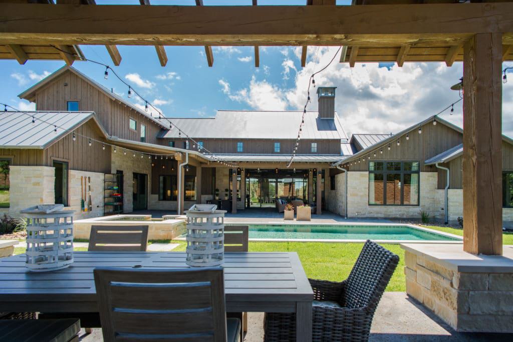 View of the house from the backyard showcasing its covered porches, a pool terrace, and a cabana.