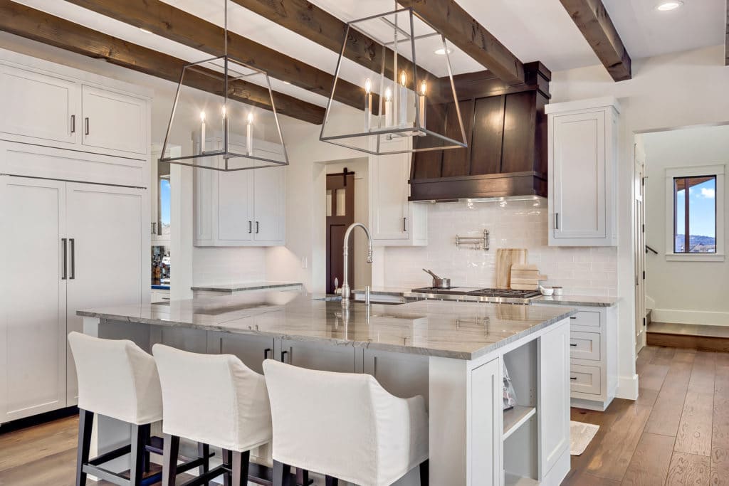 A beamed ceiling mounted with oversized pendants crowns the kitchen.