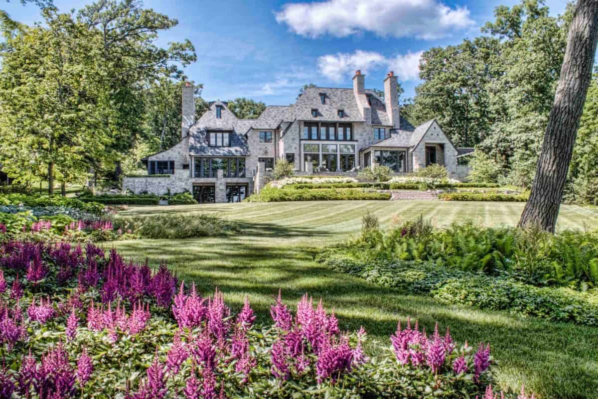 Beautiful landscaping with lush trees and colorful flowers borders the house.