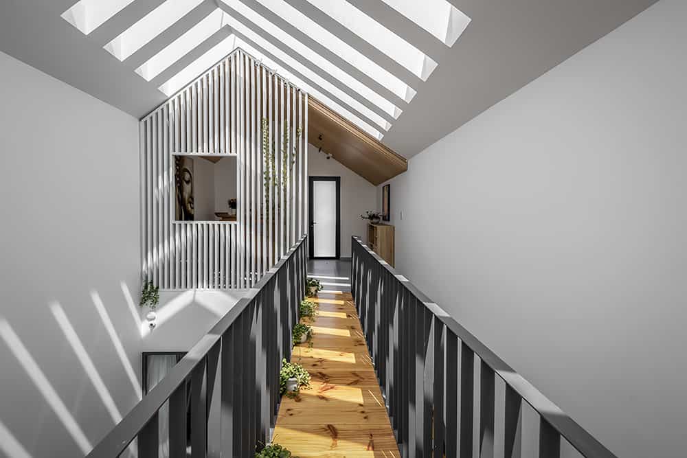 A catwalk framed with metal railings leads to another living space.