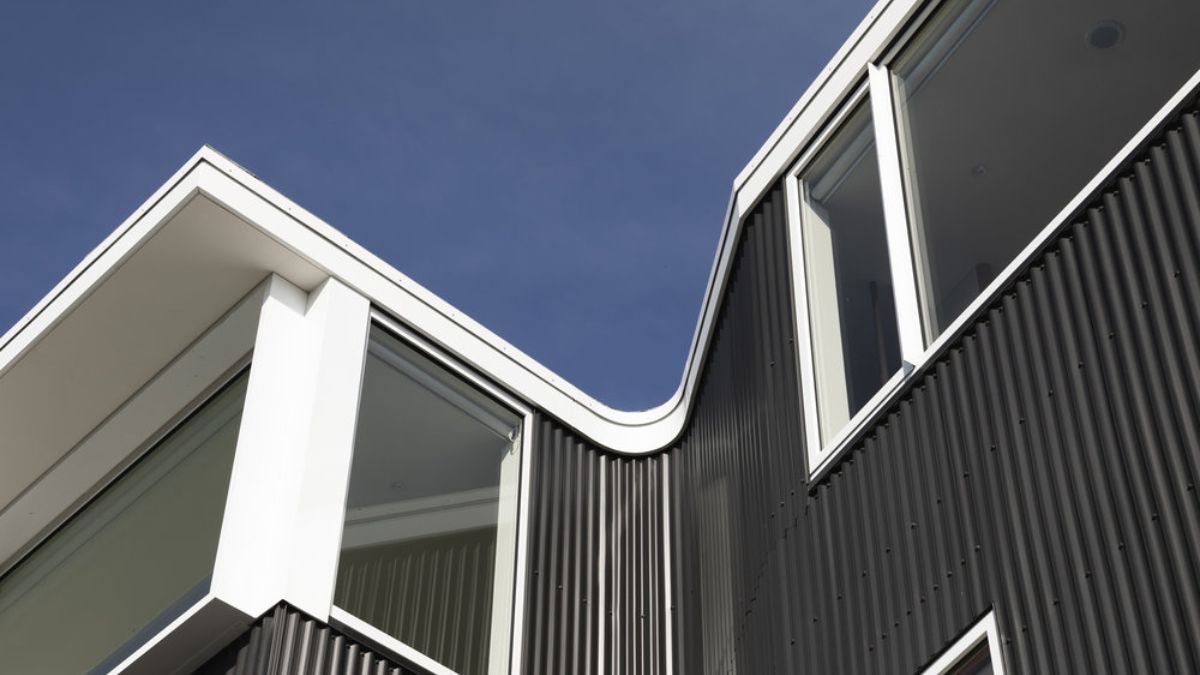 A close-up photograph of the exterior design of Salmont Place, showcasing the use of corrugated zinc cladding to create a textured aesthetic that complements the vertical lines of the building's architecture.