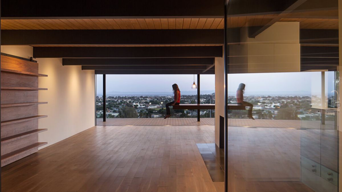 The interior of the house offers a detailed view of its ample and spacious layout, characterized by the use of large full-height glass windows that allow for an abundance of natural light and offer picturesque views of the surrounding landscape. 