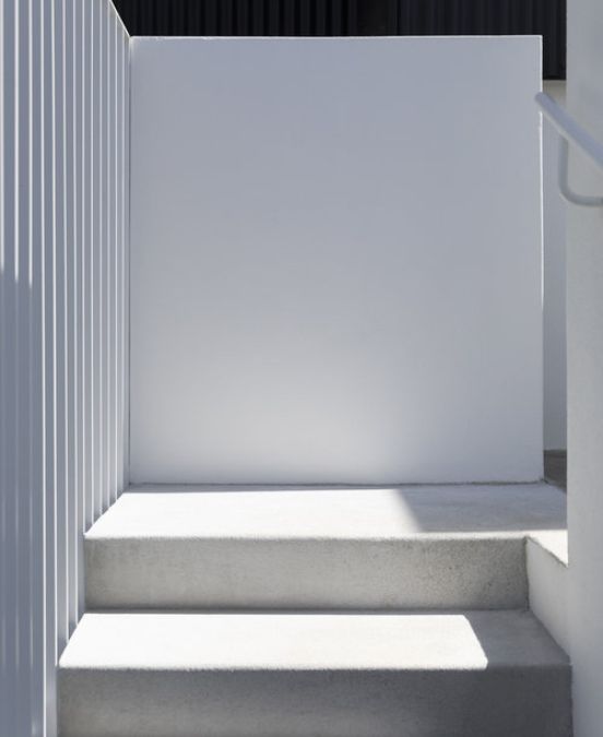 A close-up photograph of the pure white-colored exterior stairway leading to the outdoor clothes-drying area of Salmont Place house.