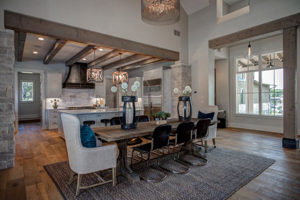 The living area also opens into the kitchen defined by brick pillars and rustic beams.